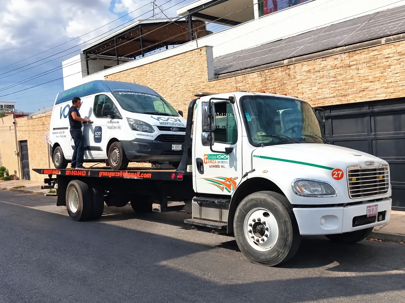 Operador de Grúas Garza asegurando una camioneta sobre grúa de plataforma en la ciudad